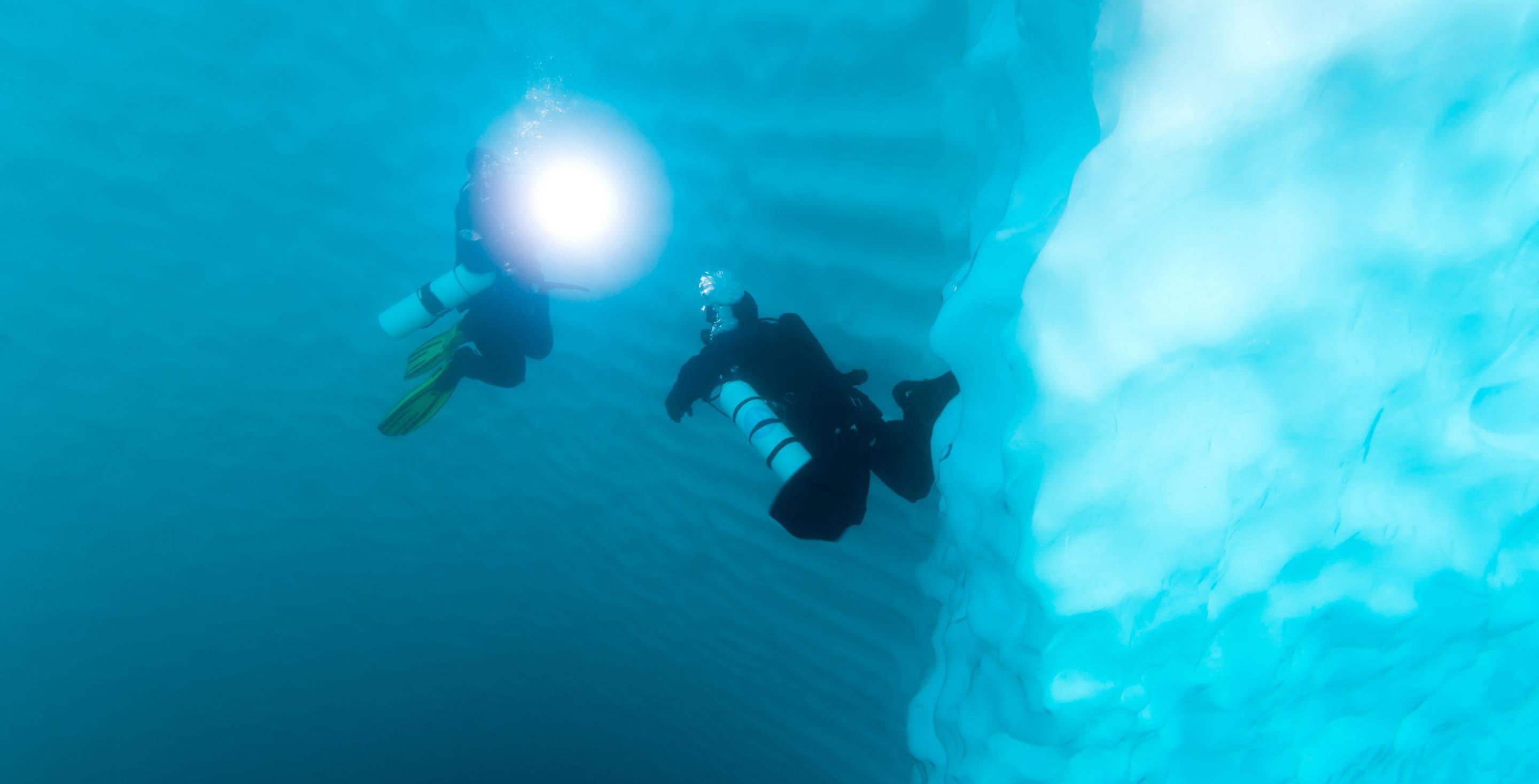 Plongeurs le long d'une paroi d'un iceberg du fjord Sermilik sur la côte est du Groenland