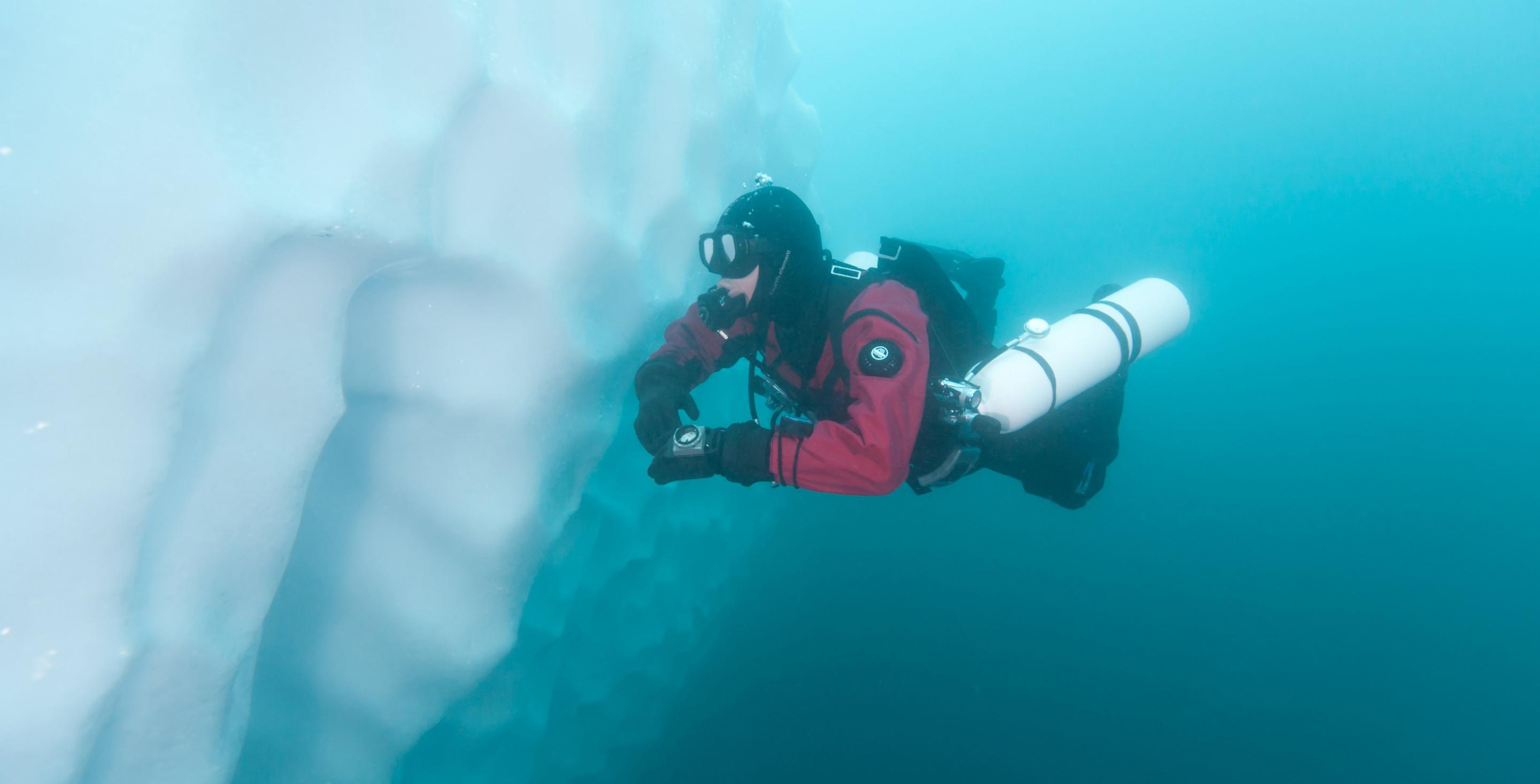 Plongeur longeant la paroi d'un iceberg dans le fjord Sermilik. La profondeur moyenne est d'environ 800 m. Côte est du Groenland